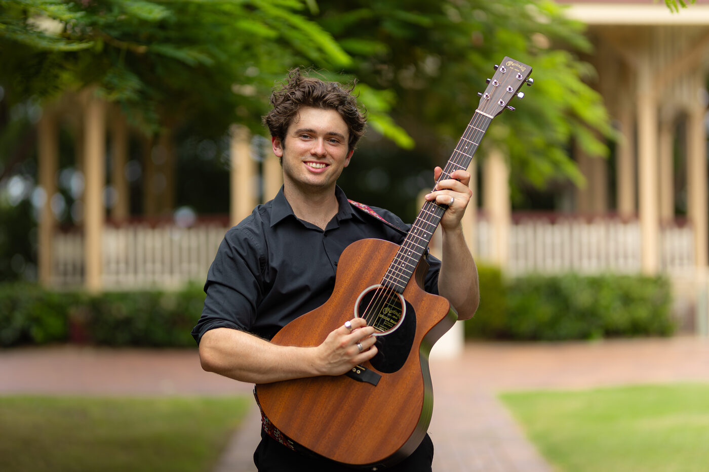 Harry Morris holding an acoustic guitar outdoors