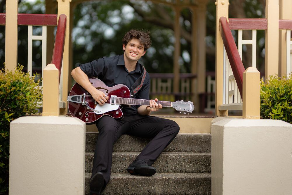 Harry Morris seated with guitar outdoors