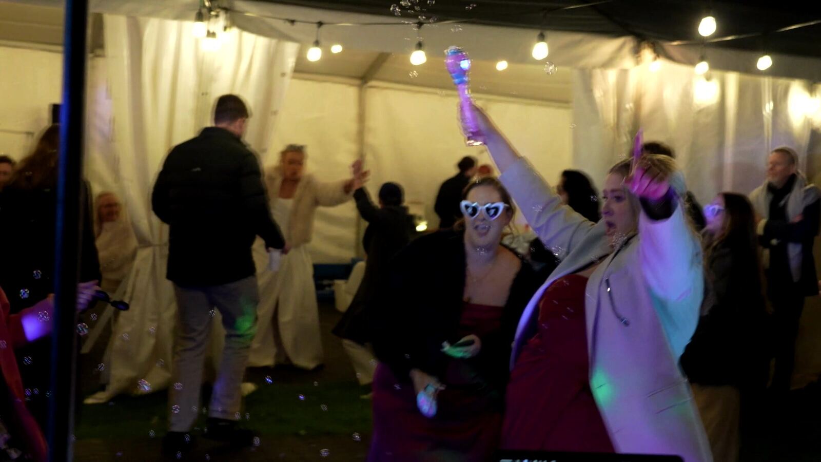 Guests dancing under marquee lighting