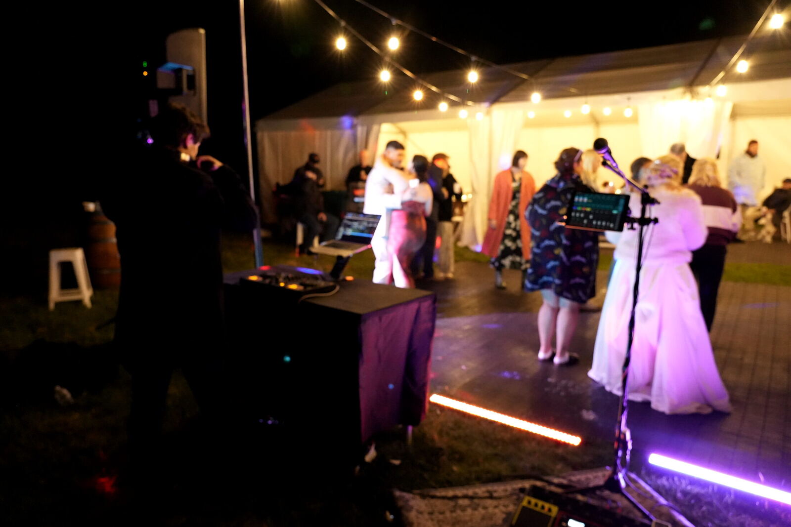 Harry Morris on the decks while guests dance under festoon lights outside a marquee at night